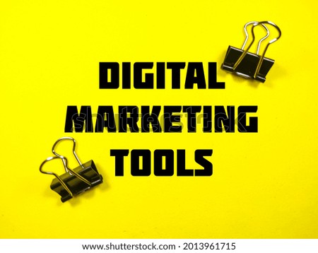 Business concept.Text DIGITAL MARKETING TOOLS with paper clips on a yellow background