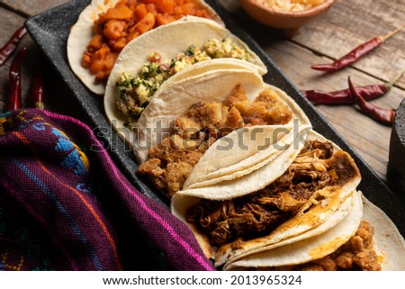 Different types of tacos also called guisados on a wooden background. Traditional mexican food