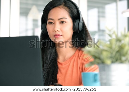 Happy asian women wearing headphone and working online with laptop computer at home office, Asia female smiling while relaxing from working 