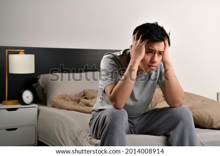 Depressed young Asian man sitting in bed cannot sleep from insomnia Royalty-Free Stock Photo #2014008914