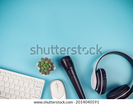 Top view or flat lay of computer keyboard  mouse, headphones, microphone and cactus on blue background with copy space. Online learning, online teaching, podcast background.