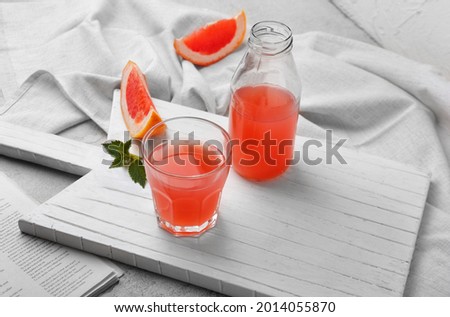 Glass and bottle of fresh grapefruit juice on table
