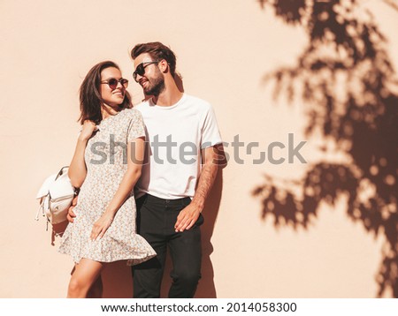 Portrait of smiling beautiful woman and her handsome boyfriend. Woman in casual summer clothes. Happy cheerful family. Female having fun. Couple posing in the street near wall in sunglasses Royalty-Free Stock Photo #2014058300