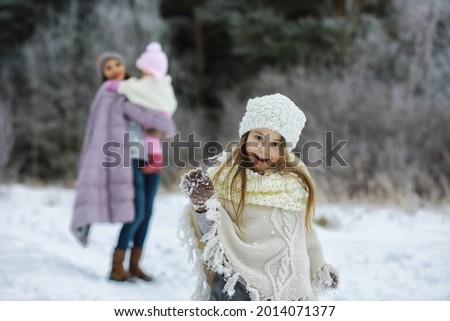 Happy family playing and laughing in winter outdoors in snow. City park winter day.
