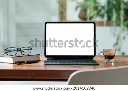 Mockup tablet with magic keyboard on wooden table in cafe with blank screen for your graphic design or product display.
