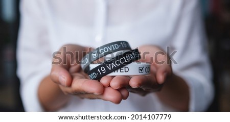 Closeup image of a woman holding Covid-19 vaccination wristband for health care concept