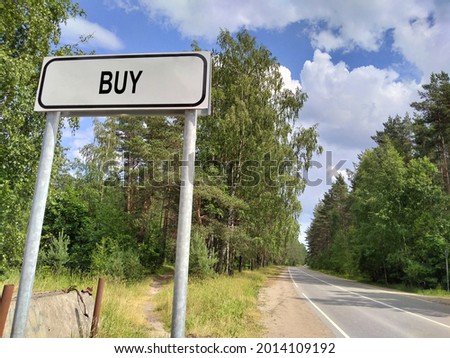 Business text - Buy, on a white sign on the background of a road in front of the city