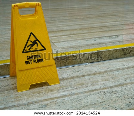 Sign showing warning of caution wet floor. one yellow plastic wet floor sign on tile floor.