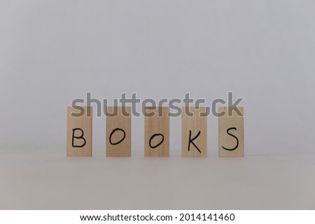 The word book written on wooden cubes and books in the background