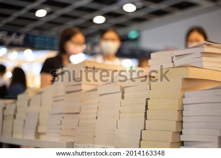 blurred young female students with face masks select and read books behind piles of books in book fair in Hong Kong during Covid-19 Royalty-Free Stock Photo #2014163348