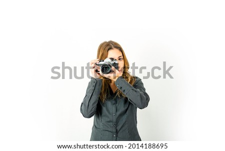 Beautiful young woman holding retro camera pointing subject and rotates focus ring on lens. Vintage versus new photography technologies at modern times.  