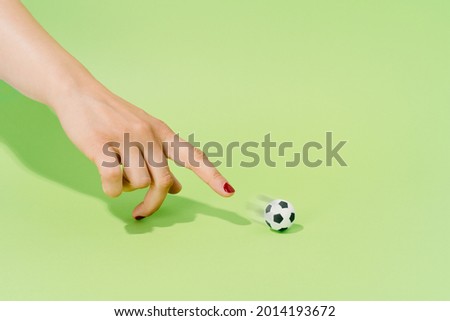 Hand of an unknown woman playing with a soccer ball on a green background. football and sport concept.