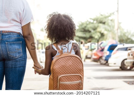little girl with backpack holds a person's hand. back to school concept.