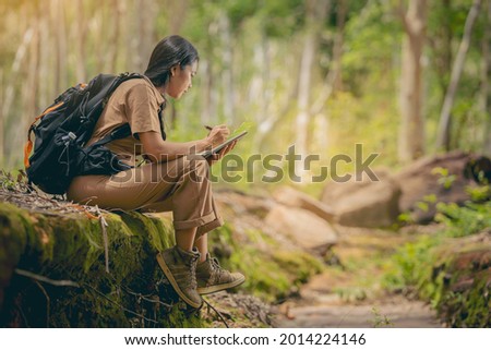 Biologist or botanist recording information about small tropical plants in forest. The concept of hiking to study and research botanical gardens by searching for information. Royalty-Free Stock Photo #2014224146