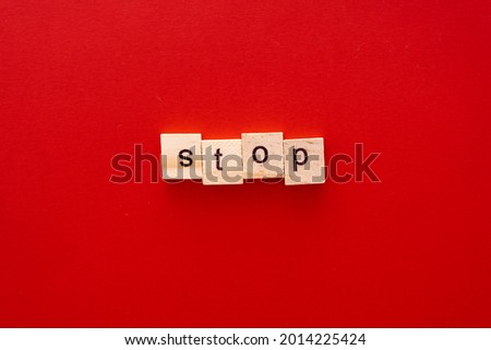 word STOP made of wooden letters on red background with copy space.