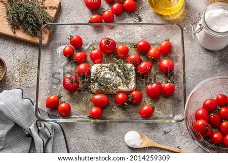 Baking dish with fresh tomatoes, feta cheese and spices on grunge background