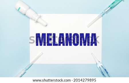 On a light blue background, syringes, a medicine bottle, an ampoule and a white sheet of paper with the text MELANOMA. Medical concept.