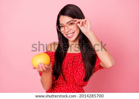 Photo of nice sweet young lady give fruit wear eyewear red dress isolated on pastel pink color background