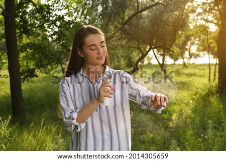 Woman applying insect repellent on arm in park. Tick bites prevention Royalty-Free Stock Photo #2014305659