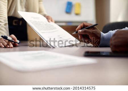 Close-up of black businessman signing an agreement in the office.