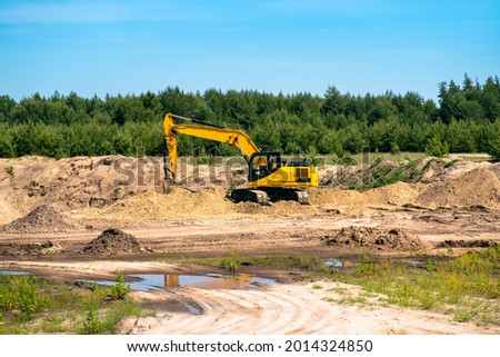 An industrial yellow excavator develops in a sandpit quarry. Industry, technology, mining. Heavy industrial machinery.