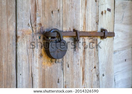 Old metallic padlock on a wooden door, close up