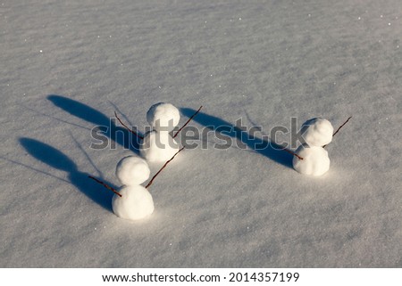 three little snowman in the winter season, the snowman is made of several parts and stands in the snow in cold weather, games in the snow with the creation of several snowman figures