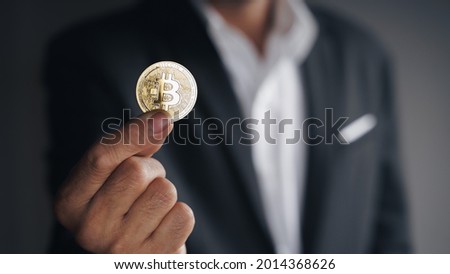 Handsome Investor Businessman in black suit holding a golden bitcoin on dark background, trading, Cryptocurrency, Digital virtual currency, alternative finance and investment Concept.
