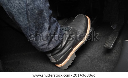 Man foot and accelerator and brake pedal inside the car or vehicle and copy space which black color leather shoe stepped on it for speed up or control automobile pace power. Automobile Driving concept Royalty-Free Stock Photo #2014368866