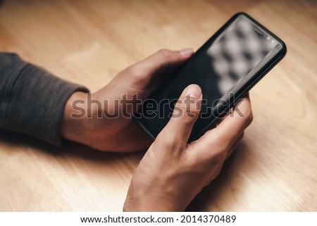 Closeup of a man using a smartphone on the wooden table, searching, browsing, social media, message, email, internet digital marketing, online shopping.
