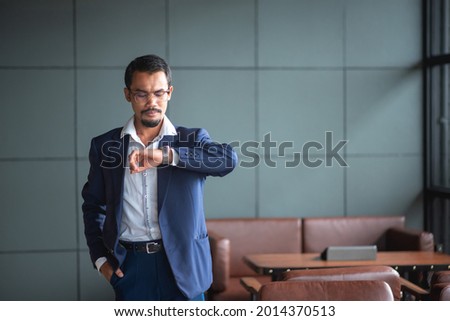 handsome young businessman wearing glasses and thinking