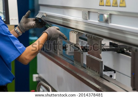 The technician operator working with hydraulic press brake bending machine. The sheet metal working operation by skill operator. Royalty-Free Stock Photo #2014378481