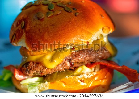 Close up on a burger at a restaurant with onion rings, cheese and vegetables