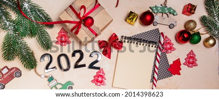Happy New Year 2022. Symbol of number 2022, Christmas tree decorations, gift box and a spiral notepad to insert the text. christmas background