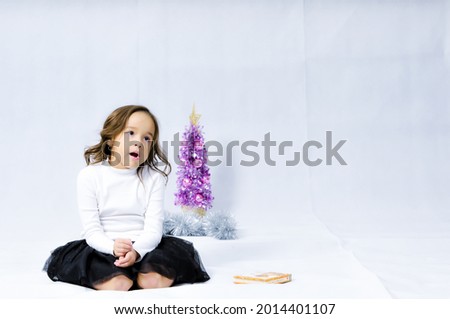 Portrait of happy pretty curly little girl   posing with Christmas decoration over white background