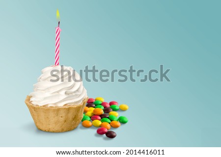Birthday cupcake with colorful birthday candles against a blue background.