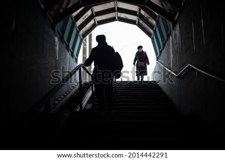 People go down the stairs. Silhouettes of people in the tunnel. Descending the subway in the city. Old people in Russia are walking along a pedestrian crossing.