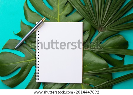 Concept love of education and business. Notepad, pen and leaf on green color background. Creative workstation flat lay.