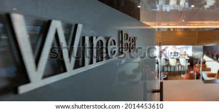 A closeup of a gray metallic  "Wine Bar" sign on the wall in a restaurant