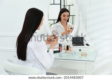 Beautiful woman applying makeup near mirror in room Royalty-Free Stock Photo #2014483007
