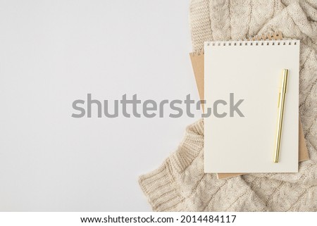Top view photo of two organizers pen and knitted pullover on isolated white background with copyspace
