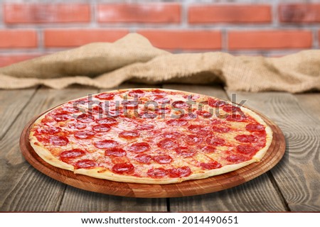 Italian pizza with sauce and greens on a wooden table