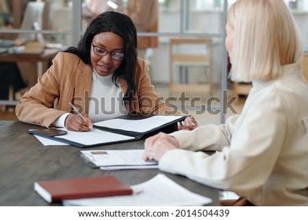 Young African applicant signing contract with new employer after interview