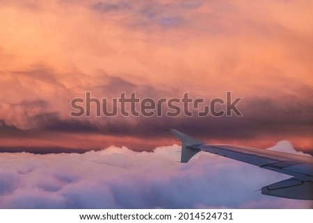 Airplane flight over the clouds at sunset