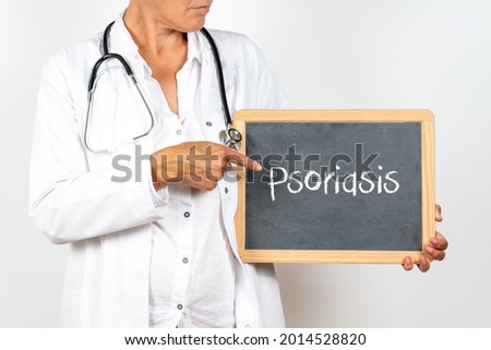 An unrecognizable doctor holding and pointing at a small blackboard with Psoriasis written on it