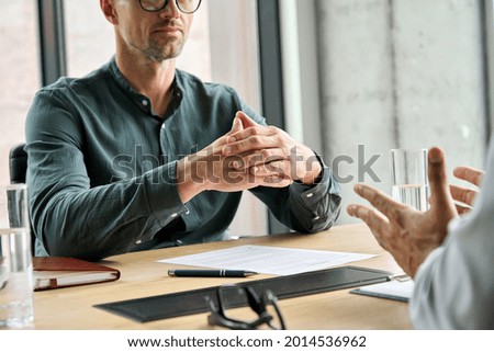 Focused executive businessman client clasped hands negotiating, thinking, making decision sitting at table listening manager partner at office negotiations meeting. Business interview concept. Closeup Royalty-Free Stock Photo #2014536962