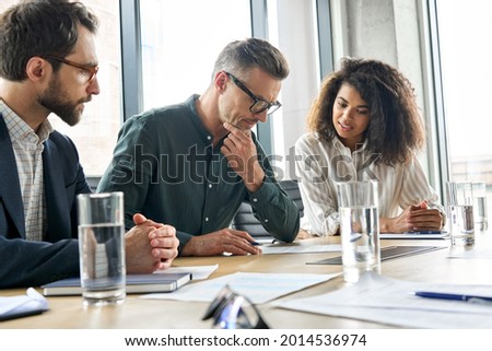 Focused doubtful mature businessman reading contract document thinking considering risks with professional lawyers legal experts executive team analyzing financial report sitting at office table. Royalty-Free Stock Photo #2014536974