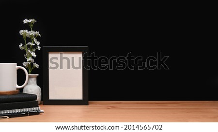 Empty picture frame, books and coffee cup on wooden table.