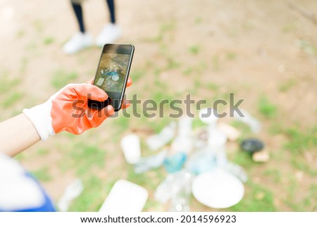 Personal perspective of a volunteer taking a picture with her smartphone of all the trash that people throw at the park  