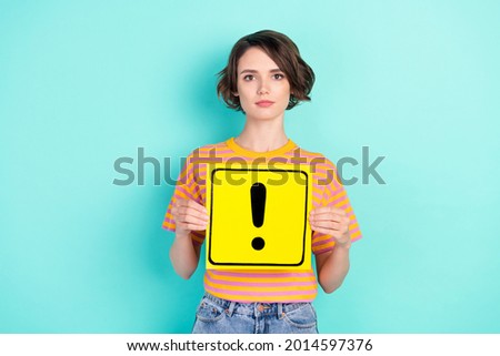 Photo of serious confident young woman dressed striped t-shirt holding exclamation point card isolated teal color background